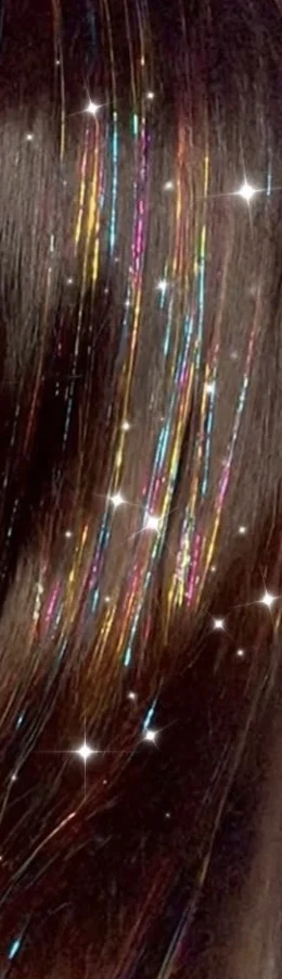 Rainbow tinsel sparkling in dark hair